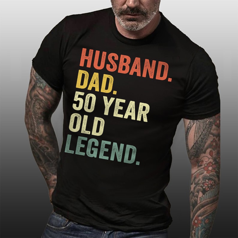 May include: Black t-shirt with a vintage-style graphic that reads "Husband. Dad. 50 Year Old Legend."