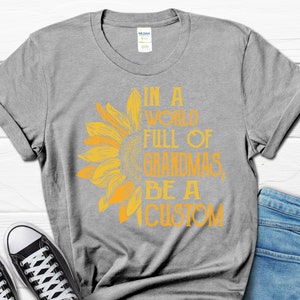 May include: Grey t-shirt with a yellow sunflower graphic and the text "In a world full of grandmas, be a custom".