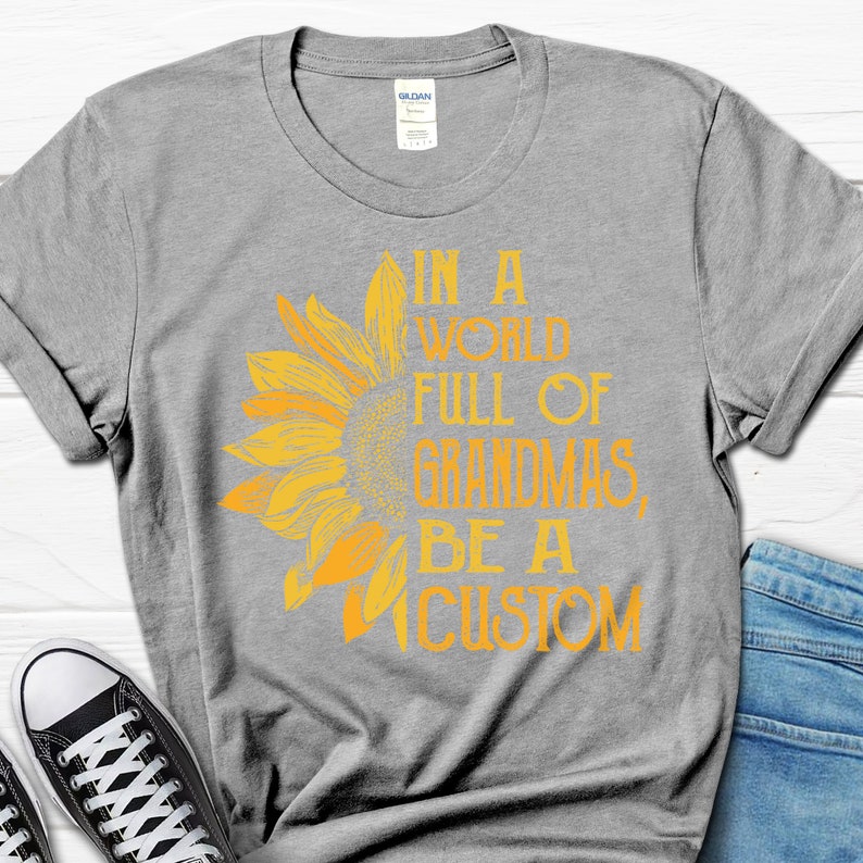May include: Grey t-shirt with a yellow sunflower graphic and the text "In a world full of grandmas, be a custom".
