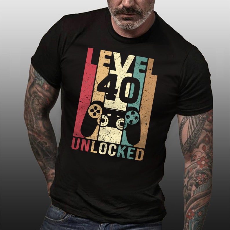 May include: A black t-shirt with a vintage-style graphic that says "Level 40 Unlocked" with a retro video game controller in the center.