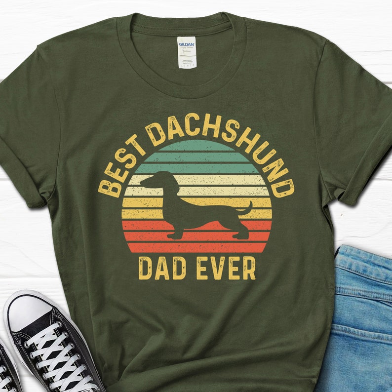 May include: A green t-shirt with a vintage-style graphic of a dachshund and the text "Best Dachshund Dad Ever".