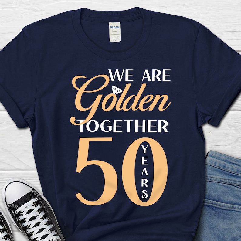 May include: Navy blue t-shirt with the text "We are Golden Together 50 Years" in white and orange. A diamond graphic is above the word "Golden".