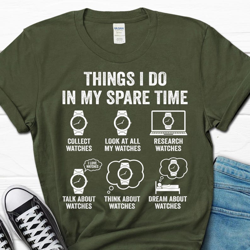 May include: Olive green t-shirt with white text and watch graphics. The text reads "THINGS I DO IN MY SPARE TIME" with phrases like "Collect Watches" and "Dream About Watches". A casual tee.