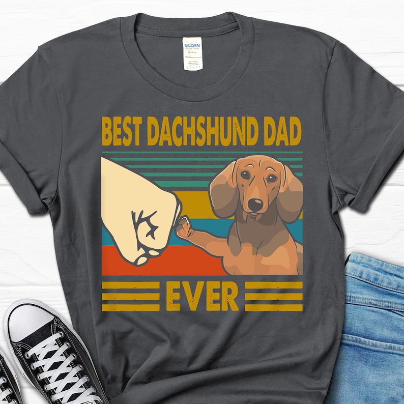 May include: A dark gray t-shirt with a vintage-style graphic featuring a dachshund dog with the text "Best Dachshund Dad Ever".