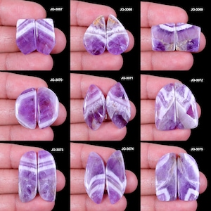 Peut inclure: Diverses paires de pierres précieuses d'améthyste polies, présentant des motifs uniques de rayures violettes et blanches. Les formes varient, incluant rectangulaire, goutte d'eau et ovale. Chaque paire est identifiée par un numéro.