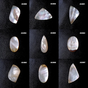 May include: Nine iridescent mother-of-pearl cabochons in various shapes, including oval, teardrop, and triangular. The cabochons have a pearlescent sheen with hints of pink, blue, and gold. Each piece is unique, with natural variations in color and pattern.