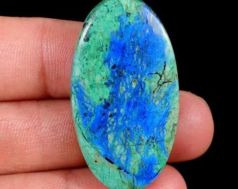 May include: An oval-shaped polished gemstone featuring a vibrant mix of bright blue and mottled green patterns with dark veining throughout. The stone displays a smooth, glossy surface texture and is labeled with the text JG-8951 in the corner.