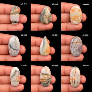 May include: A collection of nine polished cabochon gemstones in oval and teardrop shapes, each featuring unique natural patterns of gray, white, and orange veins. The stones are labeled JG-4947 through JG-4955, showcasing varied mineral inclusions.