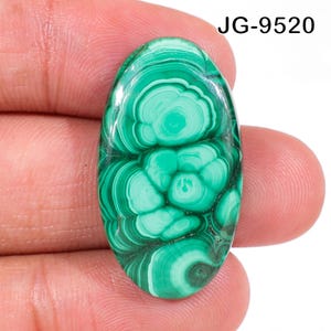 May include: An oval-shaped malachite gemstone featuring concentric bands of light and dark green patterns. The stone has a smooth, polished surface with a glossy finish. The text JG-9520 is visible in the upper right corner of the image.