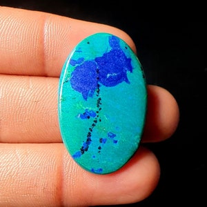 May include: Oval shaped cabochon gemstone with a blue and green pattern. The stone has a dark blue center with a green outer edge.