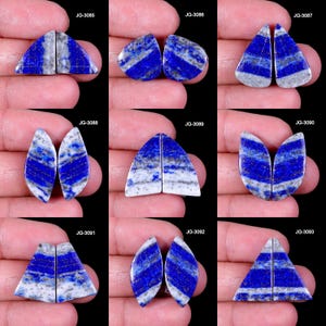 May include: A collection of nine pairs of polished lapis lazuli gemstones, each with a unique shape and pattern. The stones display a deep blue color with white and gray marbling. The gemstones are held in a person's hand against a black background.