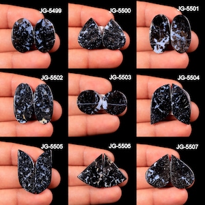 May include: Pairs of polished black gemstones with white and light blue veining, in various shapes. The gemstones are held in a person's hand. Each pair is labeled with a unique code: JG-5499, JG-5500, JG-5501, JG-5502, JG-5503, JG-5504, JG-5505, JG-5506, and JG-5507.