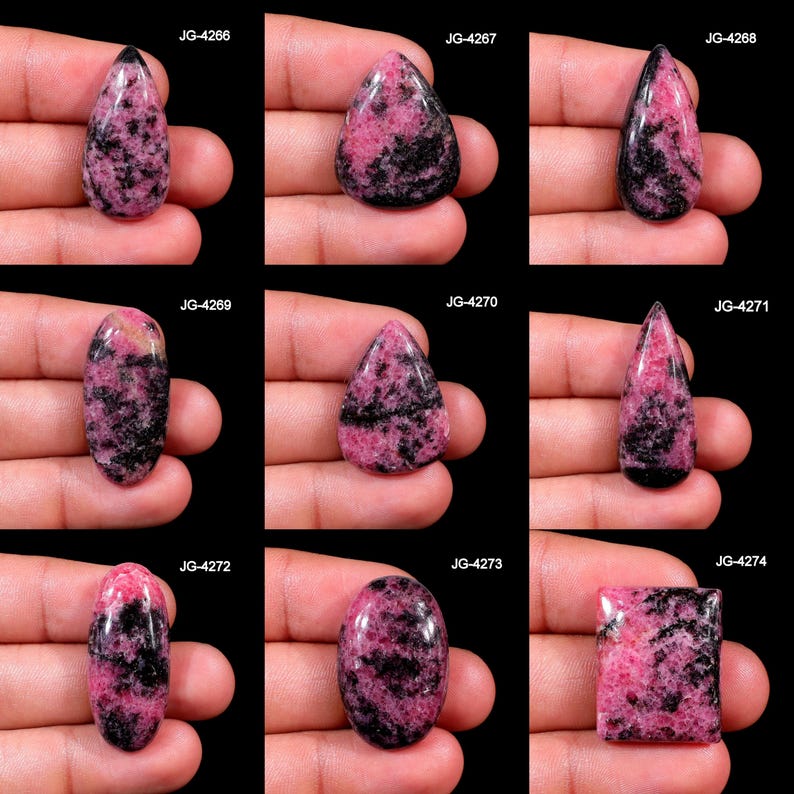 May include: Assortment of polished rhodonite gemstones in various shapes, including teardrop, oval, and rectangular. The stones display a mix of pink and black patterns. Each stone is held in a hand, with the product code visible.