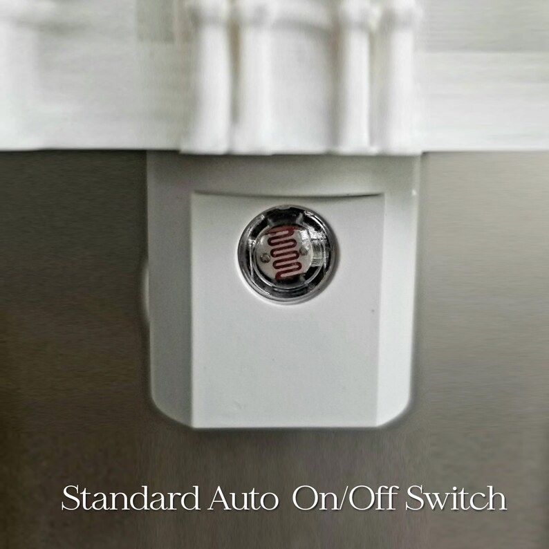 May include: A white night light with a Standard Auto On/Off Switch. The night light has a clear, circular sensor with a red, wavy filament. The night light is plugged into a wall outlet.