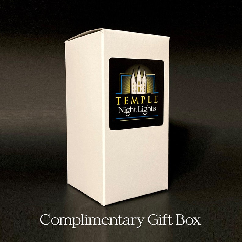May include: A white rectangular gift box with a black label featuring the text "TEMPLE Night Lights" and a graphic of a building. The box is labeled "Complimentary Gift Box" in white text at the bottom.