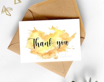 Puede incluir: Una tarjeta blanca con un diseño de salpicaduras de acuarela amarilla y el texto "Gracias" en caligrafía negra.