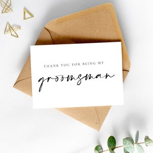 May include: A white card with black text that reads "Thank you for being my groomsman". The card is sitting on a brown envelope.