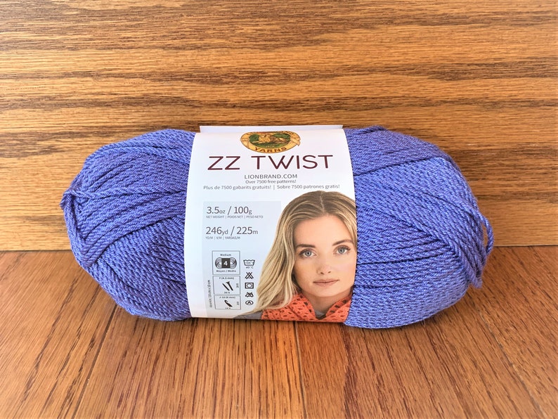 Puede incluir: Un ovillo de hilo morado etiquetado como "ZZ Twist" de Lion Brand. La etiqueta tambi&eacute;n incluye el peso, el metraje y las instrucciones de cuidado.