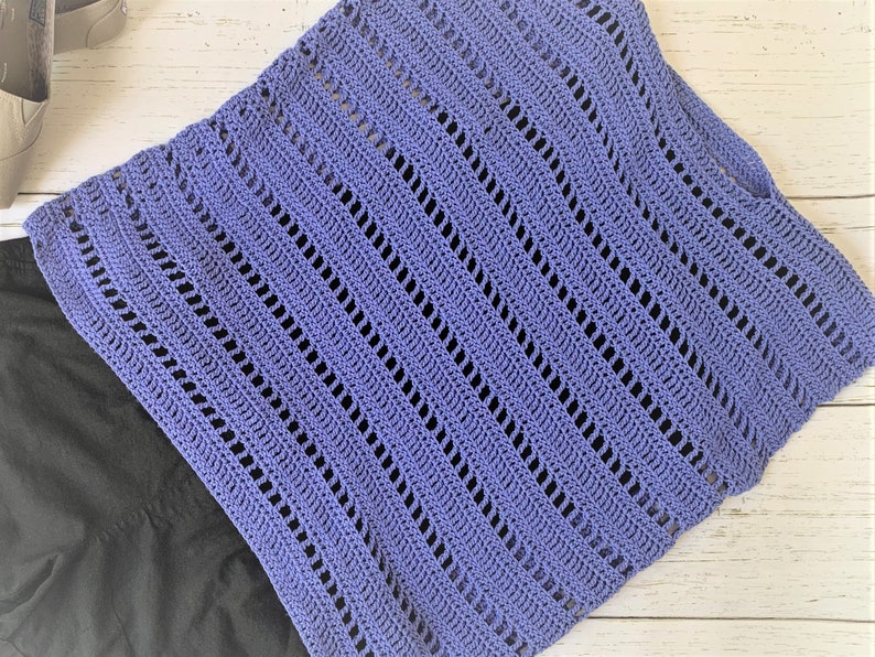 Puede incluir: Un top de ganchillo de color morado claro con un patr&oacute;n de encaje. El top est&aacute; hecho con un punto sencillo y tiene un ajuste holgado y fluido.