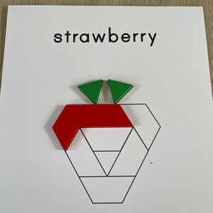 May include: A red and green geometric shape puzzle that forms a strawberry. The puzzle pieces are arranged to form a strawberry shape with green leaves on top.