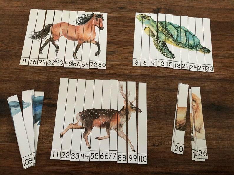 May include: A set of 10 puzzle pieces featuring different animals, including a horse, deer, turtle, dolphin, and lion. Each piece has a number printed on it, ranging from 3 to 110. The pieces are arranged in rows on a wooden surface.