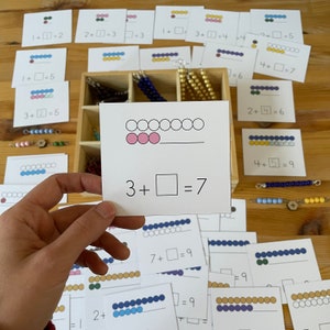 May include: A white card with a math problem, 3 +  = 7, and a visual representation of the problem using pink circles. There are seven circles in total, with three of them filled in pink.