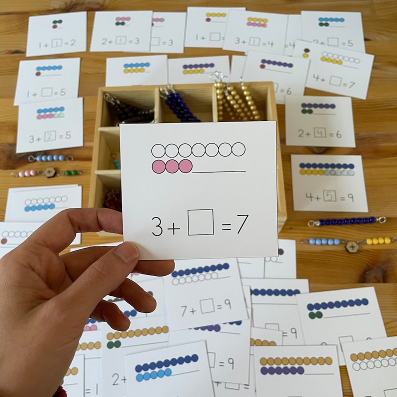 May include: A white card with a math problem, 3 +  = 7, and a visual representation of the problem using pink circles. There are seven circles in total, with three of them filled in pink.