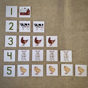 May include: A set of five cards with numbers 1 through 5 printed in green. Each card has a corresponding number of farm animals: a red barn, two cows, three chickens, four lambs, and five chicks.