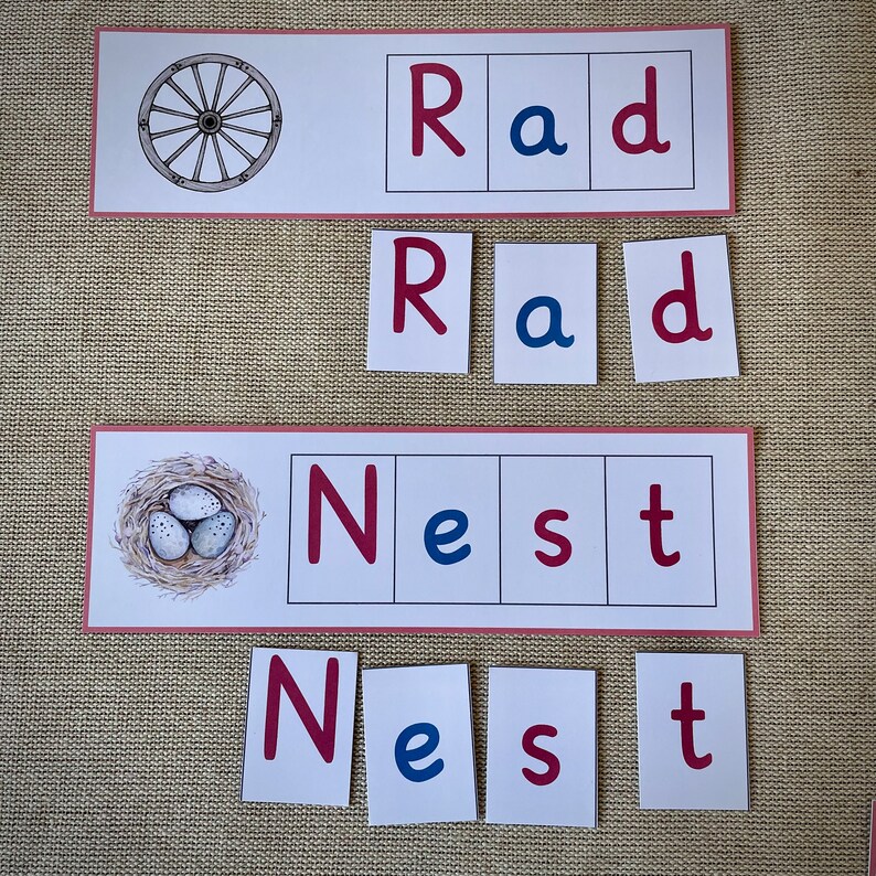 May include: A set of red and blue letter tiles spelling out the words "Rad" and "Nest". The tiles are arranged in a grid pattern. There is a picture of a wagon wheel above the "Rad" tiles and a picture of a bird's nest with eggs above the "Nest" tiles.