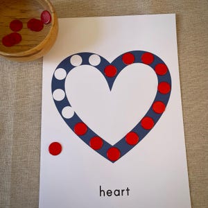 May include: A white card with a blue heart shape outlined with red circles. The word "heart" is printed below the heart. There are red circles scattered around the card.