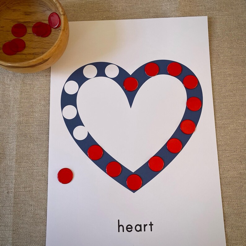 May include: A white card with a blue heart shape outlined with red circles. The word "heart" is printed below the heart. There are red circles scattered around the card.