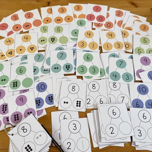 May include: A set of 20 colorful cards with numbers and dots, designed for learning math concepts. Each card features a number at the top, followed by a tree-like structure with circles representing the number. The circles contain dots to visually represent the quantity of the number.