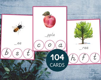 May include: A set of 104 phonics clip cards featuring watercolor illustrations of a bee, apple, and tree. Each card has a word with missing letters and a set of letter tiles to complete the word. The words are "bee", "apple", and "tree".