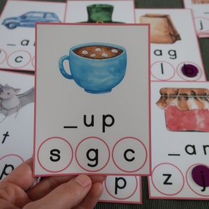 May include: A blue cup with white marshmallows in a brown liquid. The letters 's', 'g', and 'c' are in circles below the cup. The word '_up' is above the letters.