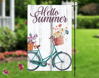 Op de afbeelding: Een wit houten bord met de tekst "Hello Summer" in paarse letters. Op het bord is een turquoise fiets met bloemen in manden afgebeeld.