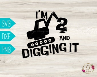 Op de afbeelding: Zwart-wit ontwerp van een graafmachine met de tekst "I'm 2 and digging it" op een houten achtergrond.