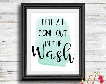 May include: A framed print with a light blue watercolor background and the text "It'll all come out in the wash" in black cursive font.