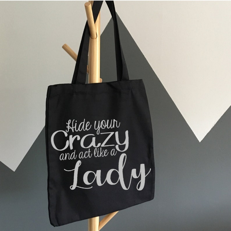 May include: Black canvas tote bag with white text that reads "Hide your crazy and act like a Lady".