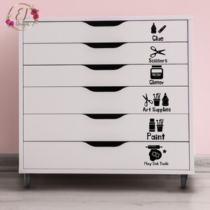 May include: White six-drawer organizer with black drawer pulls. Each drawer has a black and white label with a picture and the name of the contents. The labels read: Glue, Scissors, Glitter, Art Supplies, Paint, Play Doh Tools.