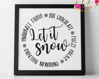 Op de afbeelding: Zwart-wit ingelijste print met de tekst "Let it snow" omringd door een cirkel met winterse woorden zoals "sneeuwballengevechten", "warme chocolademelk" en "fluffy sokken".