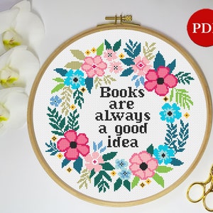 May include: A white embroidery hoop with a floral wreath design and the text "Books are always a good idea".