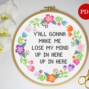May include: A cross-stitch embroidery hoop with a floral wreath design. The hoop features the text "Y'all gonna make me lose my mind up in here up in here".