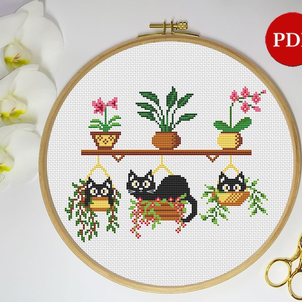 May include: Cross stitch pattern featuring three black cats in hanging planters with green plants and pink flowers. The cats are in a row, with the middle cat in the largest planter. The pattern is framed in a wooden hoop.