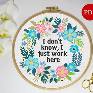 May include: Cross stitch pattern with a floral wreath and the text "I don't know, I just work here".