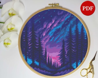 Op de afbeelding: Een kruissteekpatroon met een bos scène met een paarse en blauwe aurora borealis in de lucht. Het patroon is in een houten borduurring.