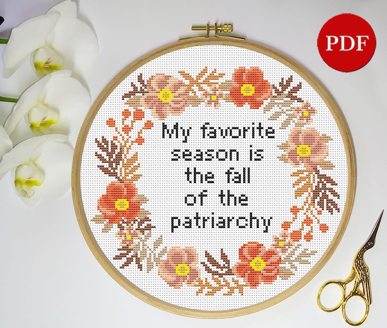 Puede incluir: Un aro de bordado de punto de cruz con fondo blanco y un dise&ntilde;o de corona floral. El texto en el centro dice "Mi estaci&oacute;n favorita es la ca&iacute;da del patriarcado".
