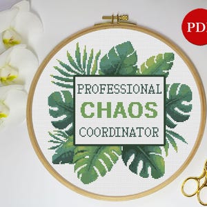 May include: Cross stitch pattern featuring a tropical leaf design with the text "Professional Chaos Coordinator".