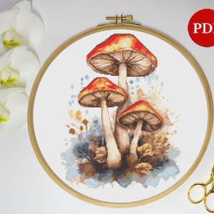 Puede incluir: Patrón de punto de cruz con tres setas rojas y marrones con manchas blancas sobre un fondo de acuarela azul y marrón.