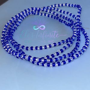 May include: Strands of blue and clear beaded jewelry are arranged on a light blue surface. The beads are small and round, creating a delicate and intricate design. The jewelry is likely worn as a waist bead or necklace.