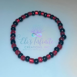May include: A red and black beaded bracelet. The bracelet is made with small, round beads. The beads are arranged in a alternating pattern of red and black.